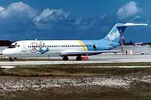 Photo de trois quart face du côté gauche d'un avion de ligne aux couleurs blanches à l'avant et bleues à l'arrière, roulant sur un aéroport.