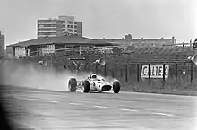 Photo en noir et blanc de la McLaren M2B disputant, sous la pluie, les essais du Grand Prix des Pays-Bas 1966