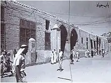 Photographie en noir et blanc montrant la foule devant les portes de la ville.