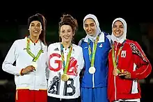 Quatre athlètes de face, posant pour les photographes, tenant leur médaille