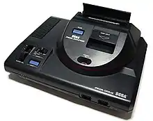 Photo d'une Mega Drive surmontée d'un boitier permettant de lire des cartouches de jeux Master System