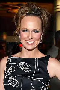 Photo d'une femme habillée d'une robe noire à motifs vue de face en train de sourire.