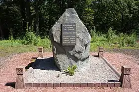 Un rocher entouré de quatre mini-chevalements en béton porte une plaque de marbre. Inscription : À la mémoire des 4 victimes de l'Étançon le 16 décembre 1950, Billequey Louis, Demesy martial, Jenroy Marius et Kortitzko Gerard.