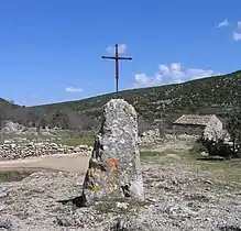 Pointe sommitale du menhir du Lacan des Lavagnes (Hérault, France), amputée et surmontée d'une croix.