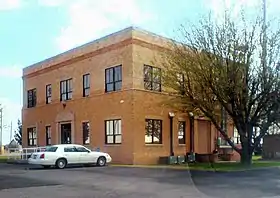 Vue d'un bâtiment de forme carré, de couleur marron, à deux étages.