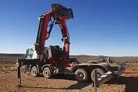 Un tracteur à 4 essieux équipé d'une puissante grue hydraulique et de barres stabilisatrices (Mercedes).