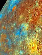 Image de Mercure présentant en bas à droite, en forme de Soleil, le cratère Kuiper. Les couleurs montrent qu'il est composé de matériaux venant de l'intérieur de la planète. Les zones bleues et sombres mettent en évidence la présence de titane. Les zones oranges très voyantes seraient composées de matériaux anciens appartenant à la croûte. La surface orangée en bas à gauche est interprétée comme étant le résultat de coulées de laves.