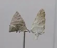 Photographie de deux pierres fines, taillées en triangle, exposées sur un présentoir dans un musée.