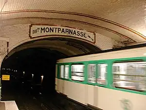 Vue d'une rame de type MF 67 et du tympan de la station Solférino indiquant "direction Montparnasse".