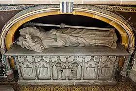 Photographie d'un tombeau sous un enfeu, avec une dalle avec un gisant qui surmonte des arcatures