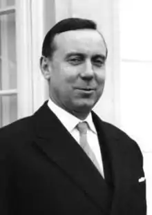 Photographie en noir et blanc de Michel Debré, haut du buste et visage. Il porte un costume noir austère mais arbore un air souriant.