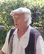 Homme avec casquette et cheveux blancs dans un parc.
