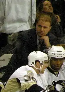 Photo de Michel Therrien accoudé derrière deux joueurs.