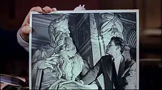 Cecil B. DeMille tenant une photo de Charlton Heston en train de regarder le Moïse de Michel-Ange. La ressemblance de l'acteur avec la sculpture l'a aidé à obtenir le rôle de Moïse.