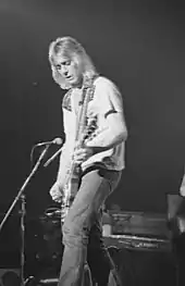 Photo en noir et blanc d'un homme blond jouant de la guitare électrique