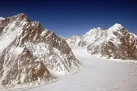 Photographie aérienne et en couleurs d'une vallée glaciaire traversant un massif montagneux.