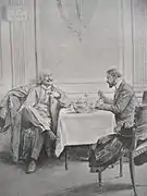 Deux hommes assis à une table en conversation dans une pièce de restaurant. L'un jambes croisées fume sous un panneau interdisant de fumer, l'autre déguste un met.