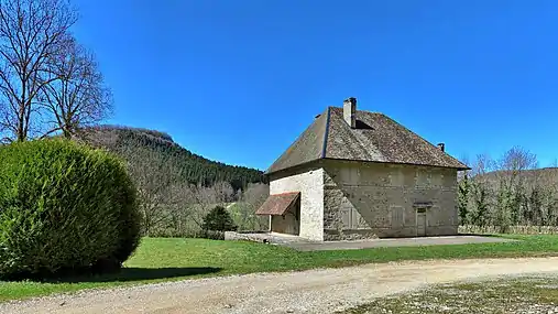 Bâtiment restauré de l'ancienne abbaye avec, au second plan, le promontoire du château de Sainte-Anne.