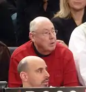 Mike Thibault vêtu d'un pull rouge observant une rencontre de basket-ball