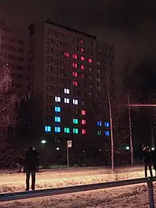 Vue nocturne d'une façade de bâtiment éclairé de façon à afficher une partie de Tetris.