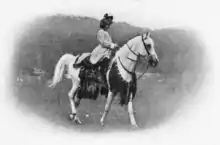 Photographie en noir et blanc représentant une jeune femme à cheval.