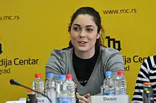 Une femme en conférence de presse devant un fond jaune.