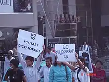 Groupe de personnes brandissant des pancartes demandant le départ de Musharraf