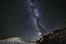 Dans une nuit saupoudrée d'étoiles, un voile blanc forme deux lignes proches d'amas parallèles.