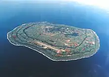 Vue aérienne couleur d'une île, dans une étendue d'eau bleue.