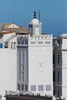 Vue sur un minaret blanc et carré.