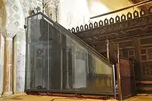 Photographie du minbar, datée de mai 2010, qui le montre protégé extérieurement par un panneau de verre.