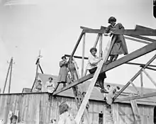 Le 26 juin 1918 près de Calais, un groupe de femmes employées comme charpentier assemblent une construction préfabriquée britannique, à usage militaire, produite par l'entreprise de Walter George Tarrant. (Durant le Premier conflit mondial, beaucoup de femmes participent à l'effort de guerre, en remplaçant les hommes partis combattre au front pour de multiples tâches jusqu'alors pourtant considérées comme masculines).