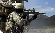Un soldat de l'US Army visant avec un SPR camouflage désert. Un désignateur laser AN/PEQ-2 est monté sur la droite du garde-main et une crosse télescopique de M4 est utilisée.