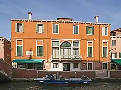 Photo couleur d'une façade de maison orangé au bord d'un canal