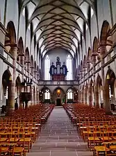 Photo de l’intérieur d'une église à voûte nervurée, dont les bas-côtés sont surmontés d'une tribune.