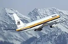 Un avion de ligne à réacteurs aux couleurs de Monarch Airlines volant au-dessus des montagnes.