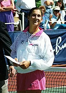 Photo de Monica Seles en 1991 lors du tournoi de San Antonio. La joueuse serre une enveloppe dans les mains et sourit.