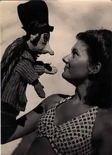 Clichet noir et blanc, vue de profil de  Monique Créteur à 16 ans, manipulant la marotte de "Lafouine", sculptée par Alphonse Réalier-Dumas en août 1947