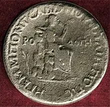 photographie d'une pièce de monnaie ; au centre une figure féminine assise