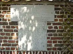 Pierres blanches gravées d'un texte sur un mur en briques.