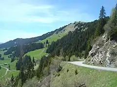 En arrière la route avant le croisement de la route du signal de Bisanne. Vue sur le Signal de Bisanne (1 941 m) plus haut