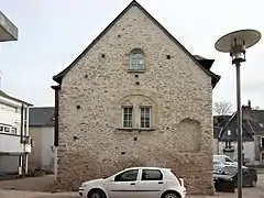 Photographie en couleurs d'une maison dont le pignon est percé de baies géminées.