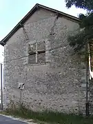 Photographie en couleurs d'une fenêtre à meneaux murée au pignon d'un édifice.