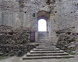 Photographie en couleurs d'une ouverture dans un mur à laquelle un escalier donne accès.