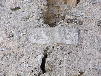 Photographie en couleurs d'une plaque de ciment recouvrant les deux lèvres d'une lézarde dans un mur.