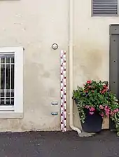 Photographie en couleurs d'une règle fixée verticalement sur un mur et indiquant des hauteurs d'eau;