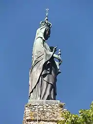 Photographie en couleurs d'une statue féminine en cuivre oxydé.
