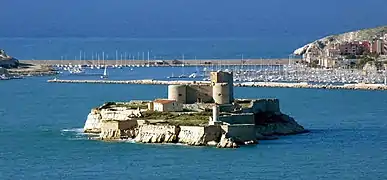 Le château d'If et son phare devant le port des îles Ratonneau et Pomègues de l'archipel du Frioul. En fond du port, la digue de Berry faisant la jonction entre les deux îles (vu depuis la corniche Kennedy de Marseille).
