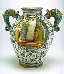 Vase ovoïde à anses en forme d'hippocampes ; l'Annonciation est peinte sur une face au centre d'un médaillon, de l'autre côté un cartouche médicinal, Montelupo Fiorentino, XVIe – XVIIe siècle.