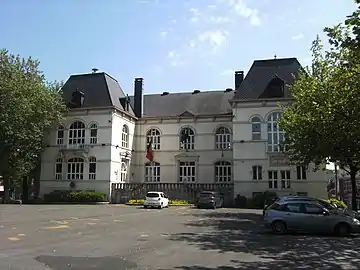 Place publique arborée avec un gros bâtiment blanc de style néo-classic